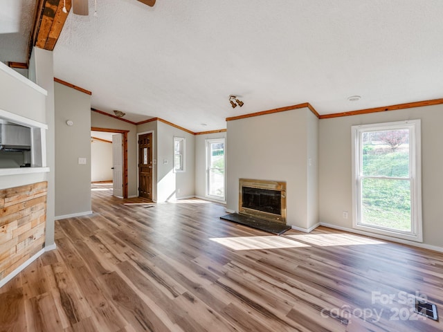 unfurnished living room with light hardwood / wood-style flooring, a healthy amount of sunlight, a textured ceiling, and ornamental molding