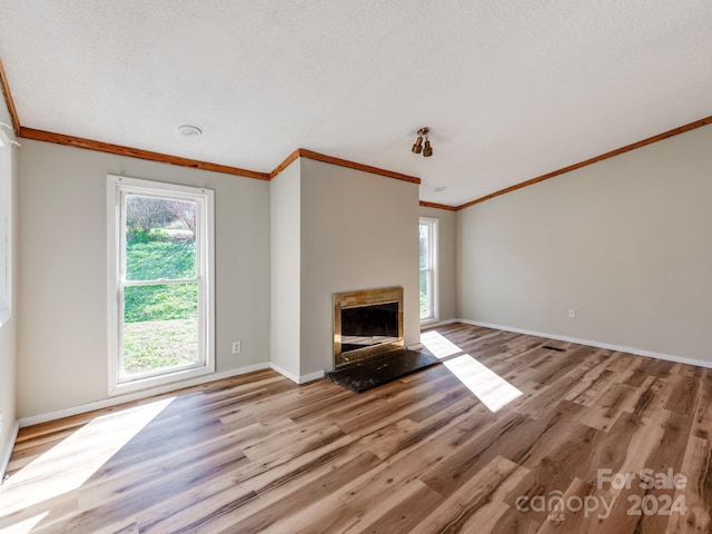 unfurnished living room with a textured ceiling, light hardwood / wood-style flooring, and crown molding