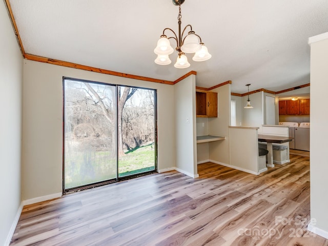 interior space featuring separate washer and dryer, light hardwood / wood-style floors, crown molding, and a notable chandelier