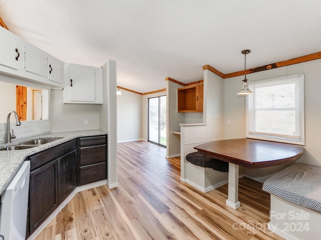 kitchen featuring light stone countertops, sink, hanging light fixtures, light hardwood / wood-style flooring, and white cabinets