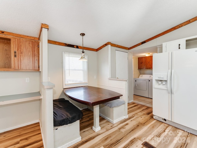 unfurnished dining area with washing machine and clothes dryer, light hardwood / wood-style floors, a textured ceiling, lofted ceiling, and ornamental molding