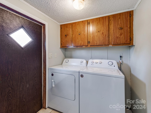 laundry area featuring cabinets, a textured ceiling, ornamental molding, and washing machine and clothes dryer