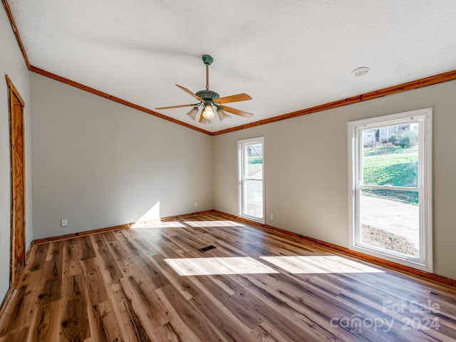 unfurnished room featuring hardwood / wood-style floors, plenty of natural light, and a textured ceiling