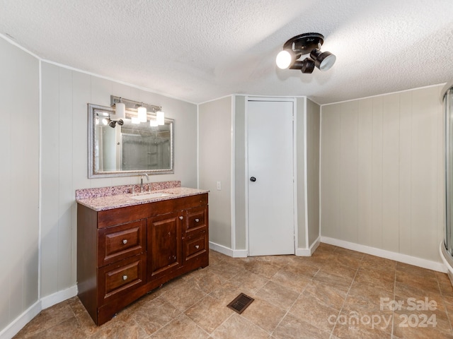 bathroom with wood walls, vanity, and a textured ceiling