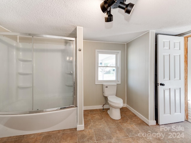 bathroom featuring combined bath / shower with glass door, a textured ceiling, toilet, and tile patterned flooring