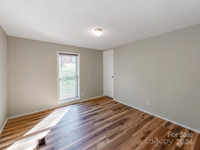 unfurnished room with wood-type flooring and a textured ceiling