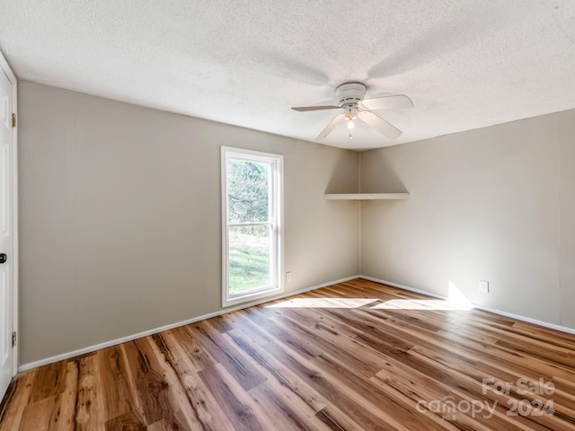 empty room with ceiling fan, light hardwood / wood-style floors, and a textured ceiling