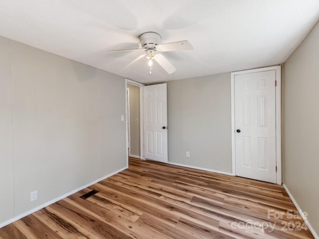 unfurnished bedroom with ceiling fan, light wood-type flooring, and a textured ceiling