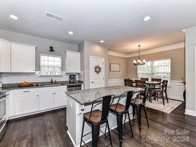 kitchen with white cabinetry, a kitchen breakfast bar, dark hardwood / wood-style floors, dark stone counters, and a kitchen island