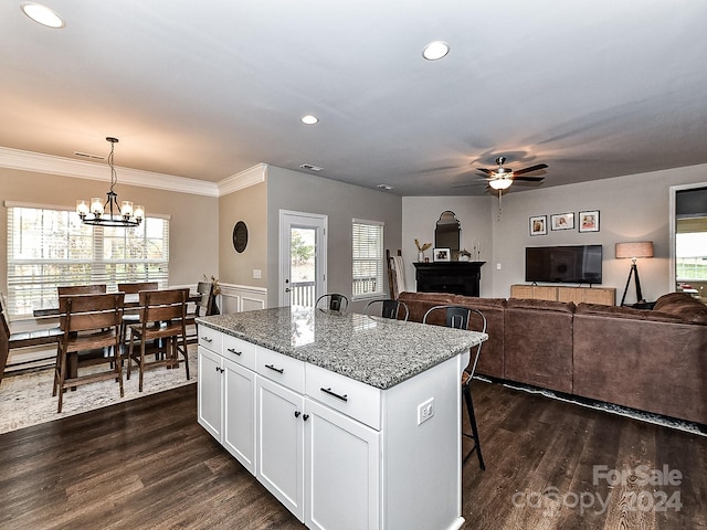 kitchen featuring white cabinets, decorative light fixtures, a kitchen island, and dark wood-type flooring