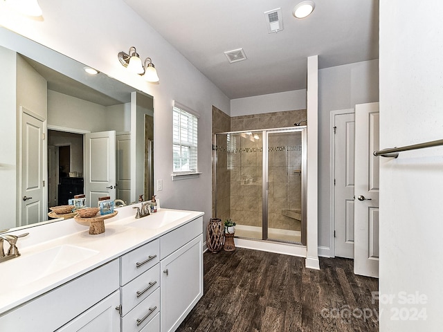 bathroom with hardwood / wood-style floors, vanity, and a shower with door