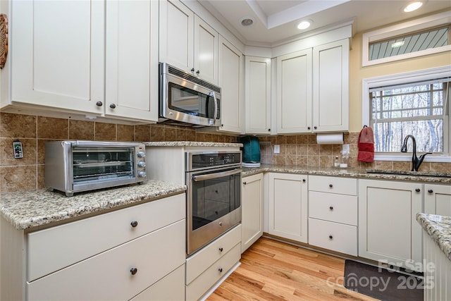 kitchen featuring a toaster, appliances with stainless steel finishes, a sink, and tasteful backsplash