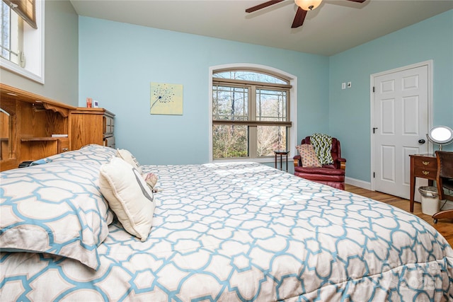 bedroom with a ceiling fan, baseboards, and wood finished floors