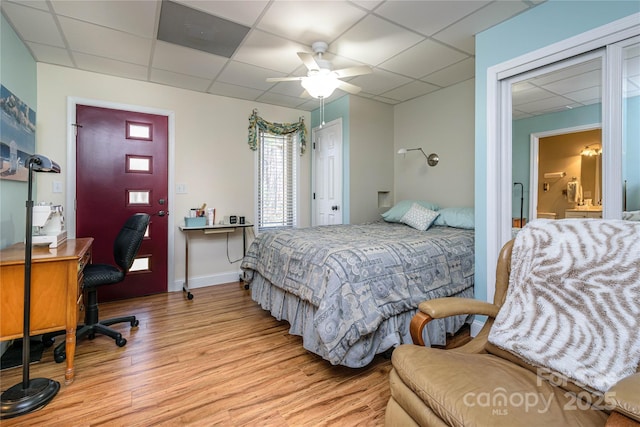 bedroom with baseboards, wood finished floors, a paneled ceiling, and a ceiling fan