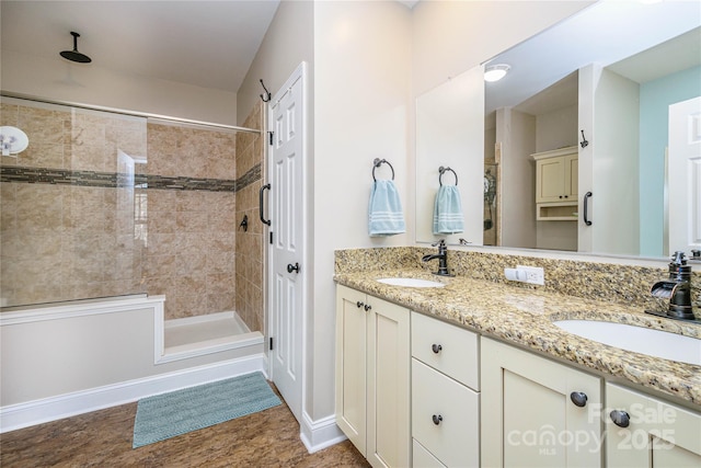 full bath with double vanity, baseboards, a tile shower, and a sink