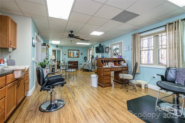 misc room featuring a paneled ceiling, baseboards, ceiling fan, and light wood finished floors