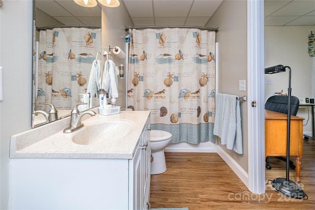 full bathroom with a drop ceiling, vanity, toilet, and wood finished floors