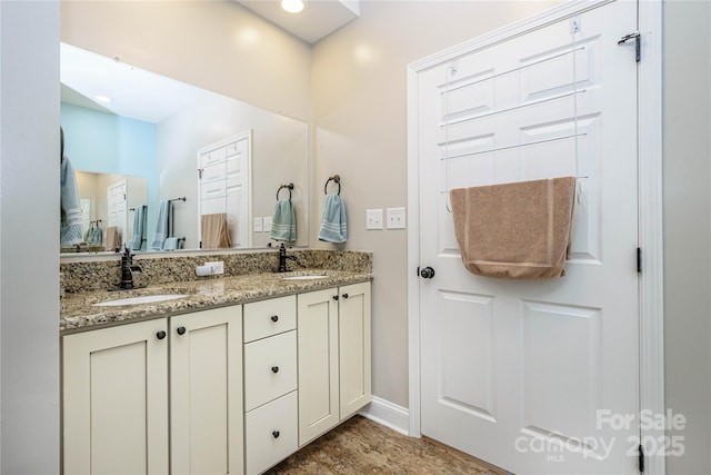 bathroom with double vanity, a sink, and baseboards