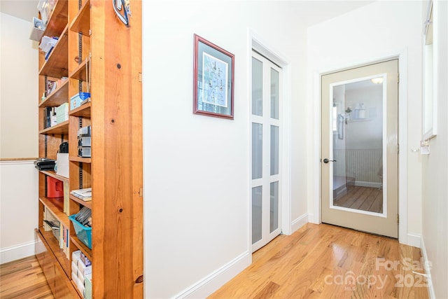 hall featuring french doors, baseboards, and wood finished floors