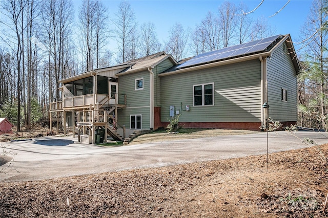 rear view of house featuring stairs, a sunroom, and roof mounted solar panels