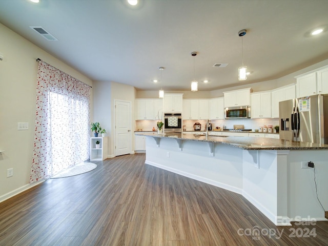 kitchen with appliances with stainless steel finishes, dark hardwood / wood-style floors, white cabinetry, and pendant lighting