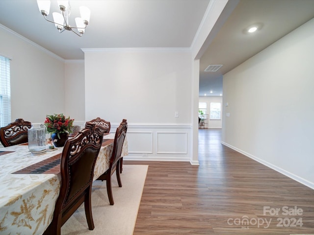 dining area featuring hardwood / wood-style flooring, a notable chandelier, and crown molding