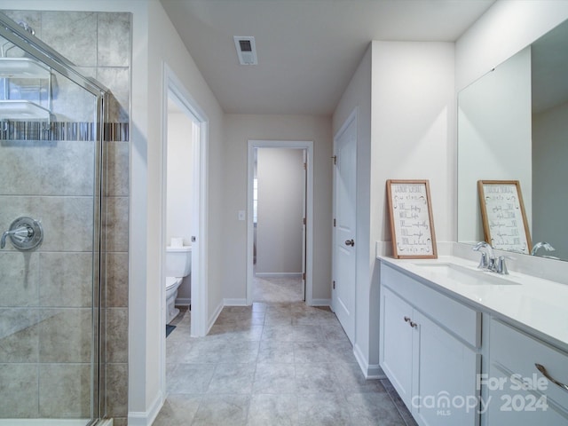 bathroom with tile patterned floors, vanity, toilet, and a shower with door