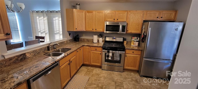 kitchen with stainless steel appliances, hanging light fixtures, sink, and dark stone counters