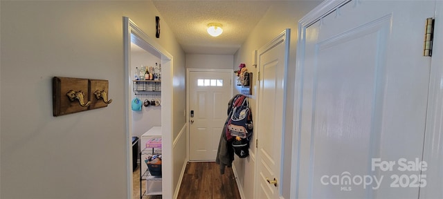 doorway to outside featuring dark wood-type flooring and a textured ceiling