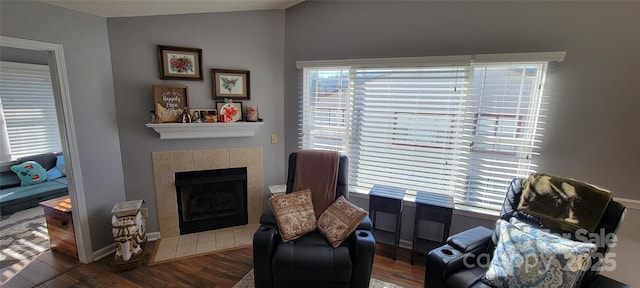 sitting room with lofted ceiling, a tiled fireplace, and wood-type flooring