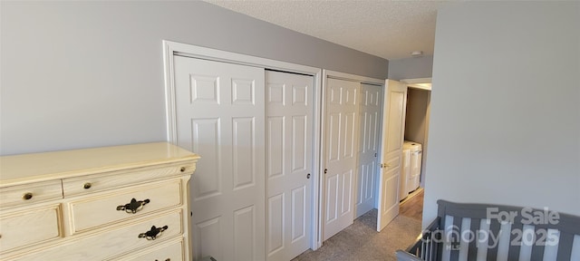 carpeted bedroom featuring two closets, washer and clothes dryer, and a textured ceiling