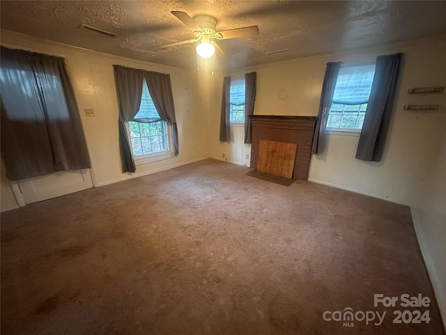 unfurnished living room featuring a textured ceiling, carpet floors, plenty of natural light, and ceiling fan