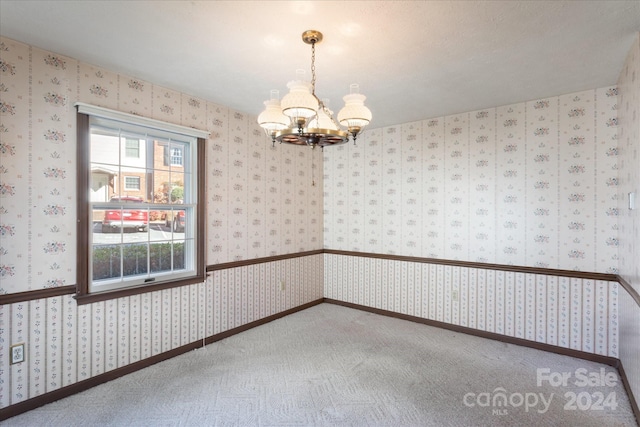 empty room featuring carpet floors and a chandelier