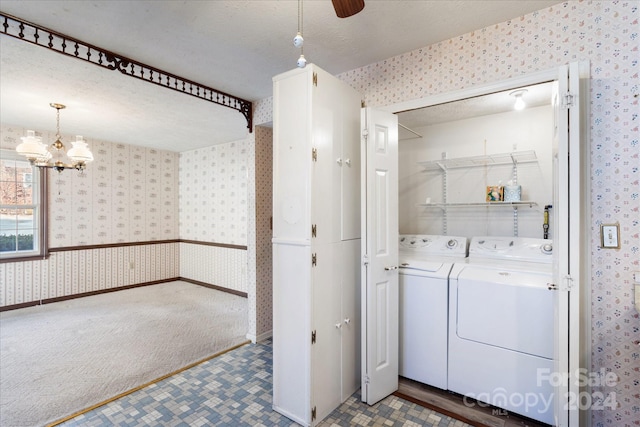 clothes washing area featuring a chandelier, a textured ceiling, carpet floors, and washer and clothes dryer