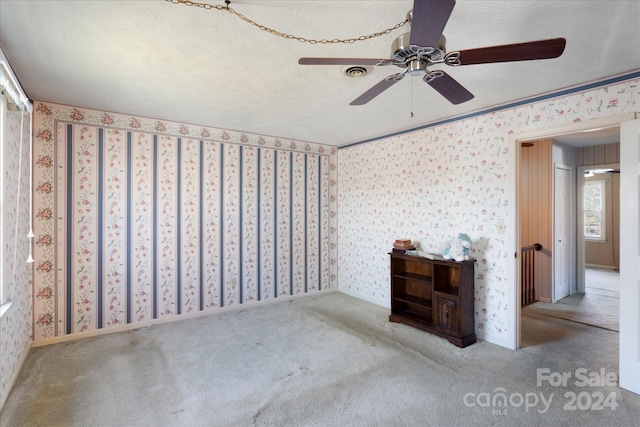 carpeted empty room featuring ceiling fan and a textured ceiling