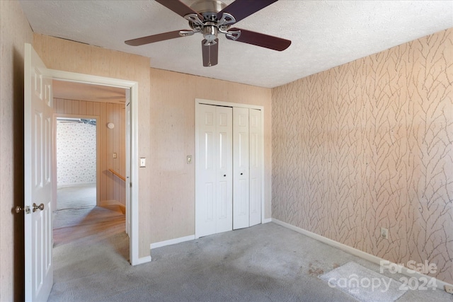 unfurnished bedroom with ceiling fan, carpet floors, a textured ceiling, and a closet