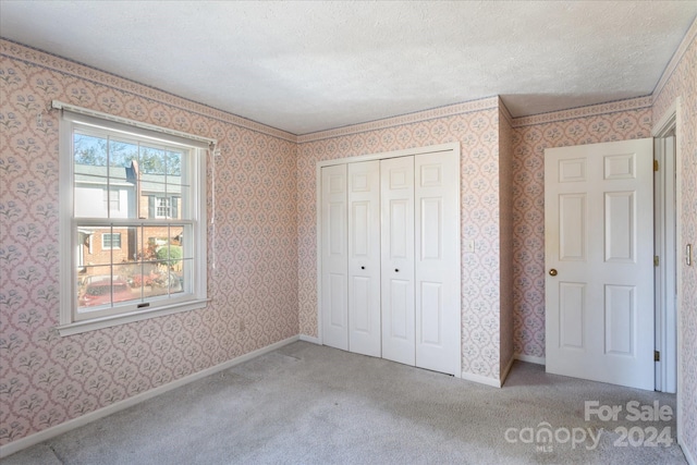 unfurnished bedroom with carpet flooring, a textured ceiling, and a closet