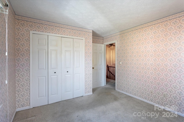 unfurnished bedroom with a textured ceiling, light colored carpet, and a closet