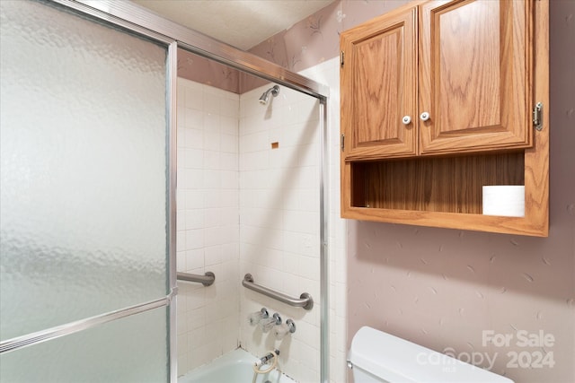 bathroom with combined bath / shower with glass door and toilet