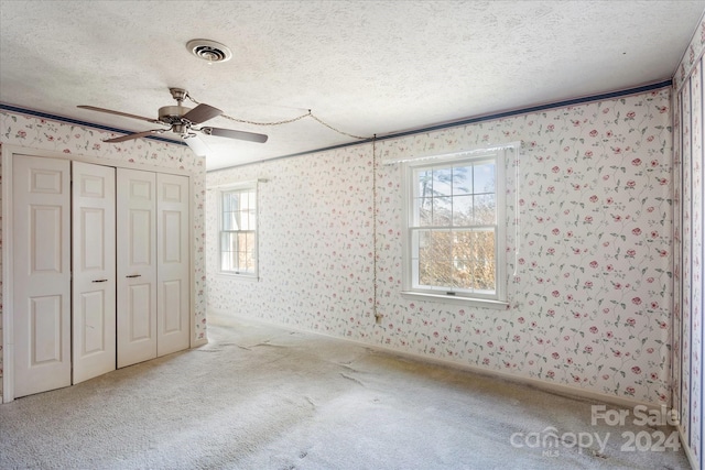 unfurnished bedroom featuring multiple windows, ceiling fan, and a textured ceiling