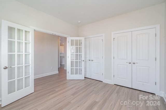 unfurnished bedroom with french doors and light hardwood / wood-style floors