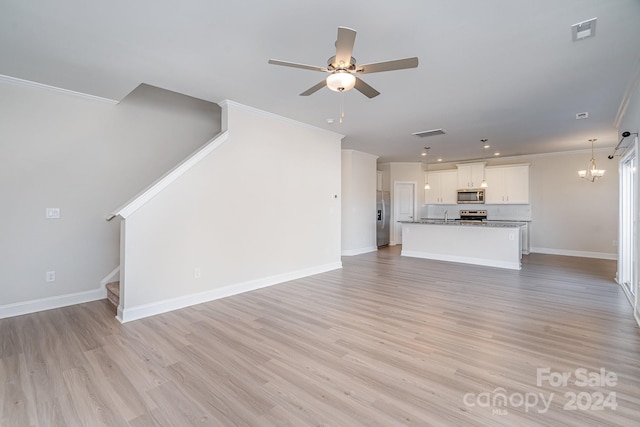 unfurnished living room with ceiling fan with notable chandelier, light hardwood / wood-style flooring, and crown molding