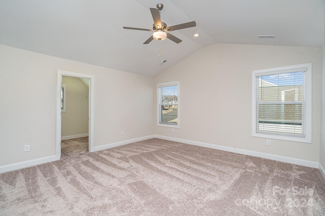 carpeted empty room with ceiling fan, plenty of natural light, and lofted ceiling