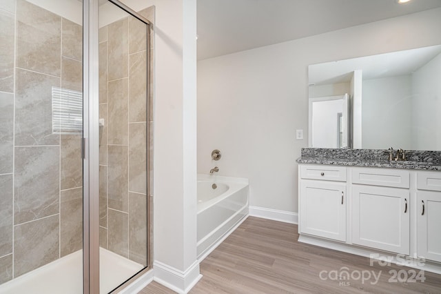 bathroom featuring vanity, wood-type flooring, and plus walk in shower