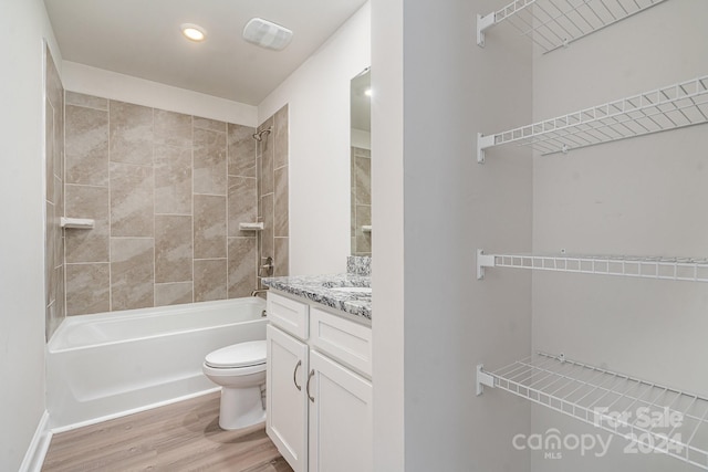 full bathroom with hardwood / wood-style floors, vanity, toilet, and tiled shower / bath combo