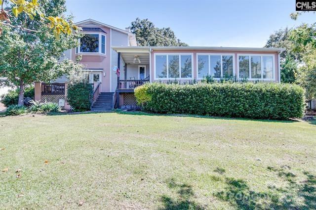 split level home with a front lawn, a wooden deck, and a sunroom