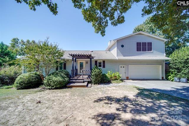 view of front of property with a garage, driveway, and a pergola