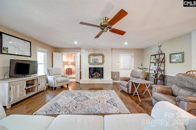 living area featuring a large fireplace, a textured ceiling, light wood-type flooring, and recessed lighting