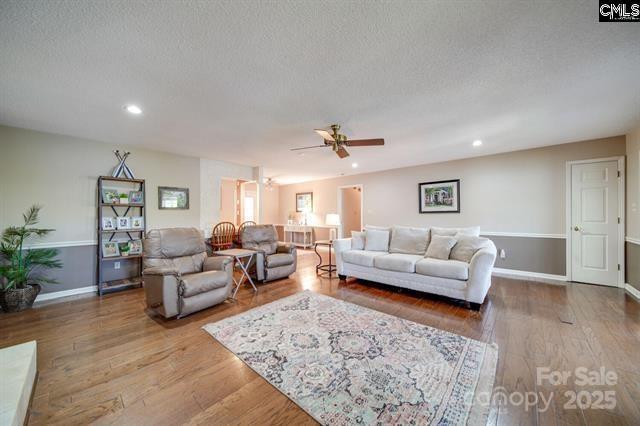 living area featuring a textured ceiling, wood finished floors, and recessed lighting