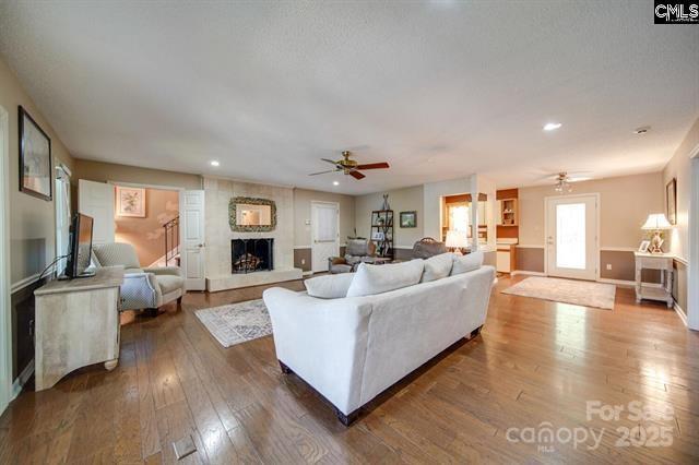 living room featuring a fireplace, a ceiling fan, wood finished floors, and recessed lighting